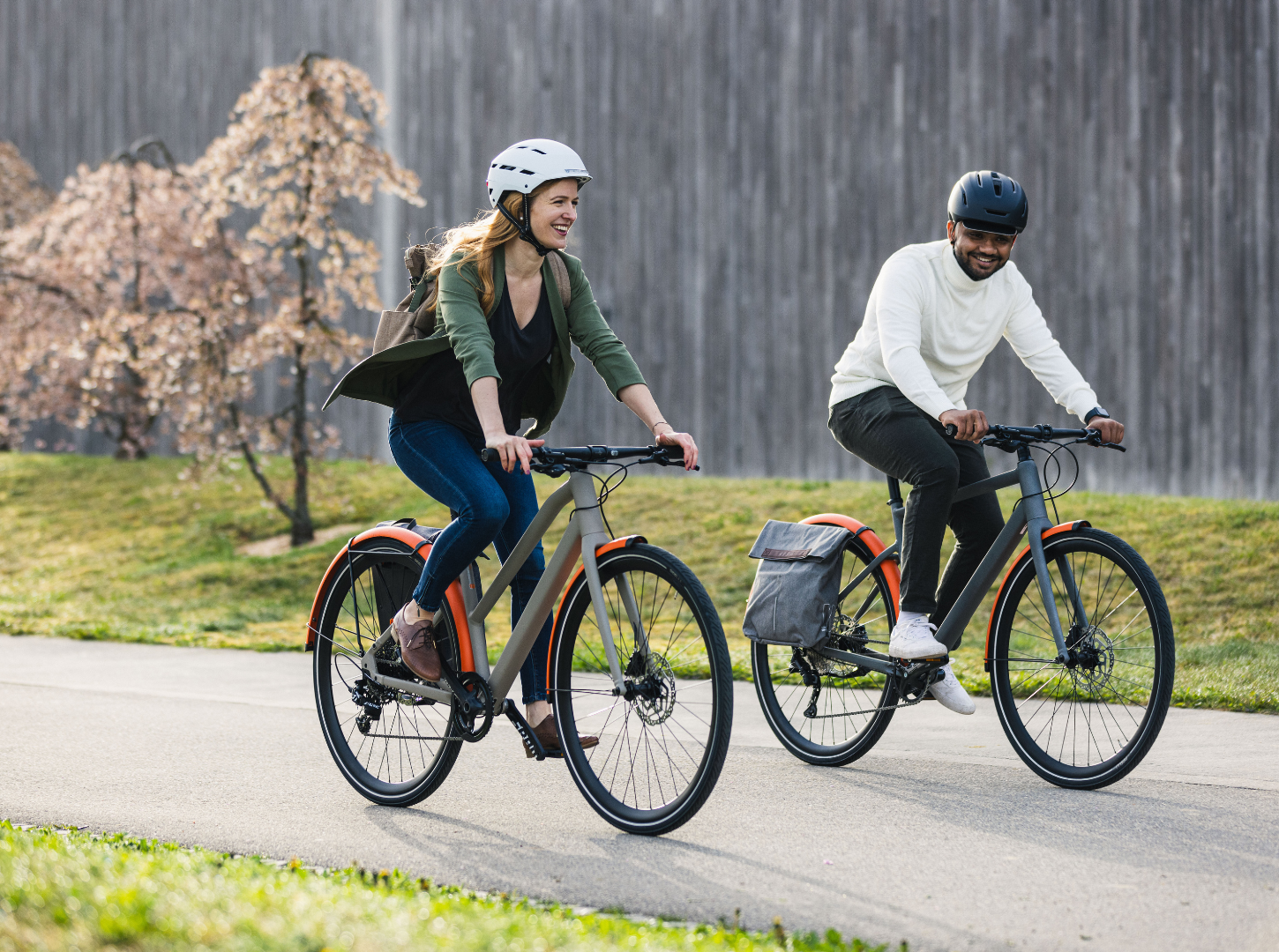 Zwei-Radfahrer-in-der-Stadt-mit-Citybikes_BMC-257-Modelle Eine lächelnde Frau und ein lächelnder Mann fahren mit ihren BMC 257 City Bike Modellen durch die Stadt